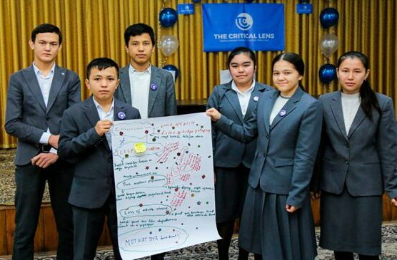 Six teens (3 girls and 3 boys) in school uniforms pose for a photo. They are displaying a large sheet of paper with their writing across it.
